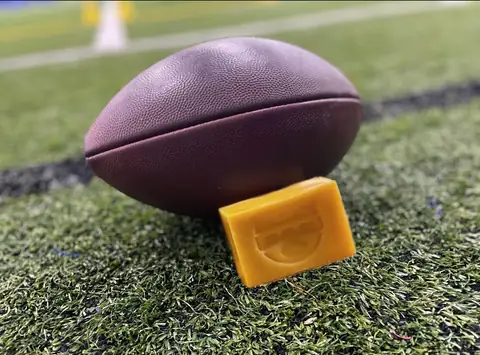 A Tacky Bar leaning against a football on stadium turf